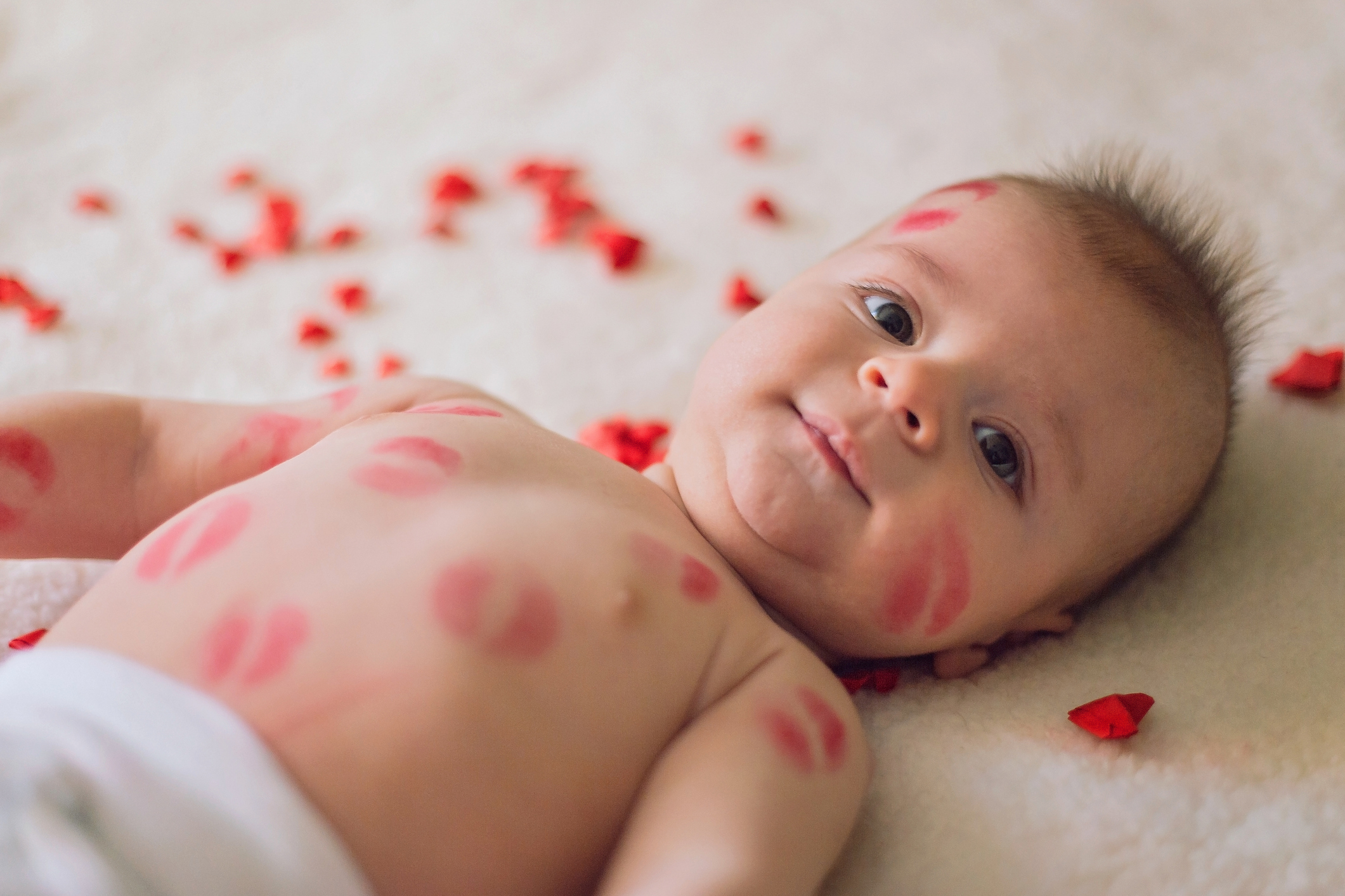 Adorable baby boy covered with lipstick kisses all over the body