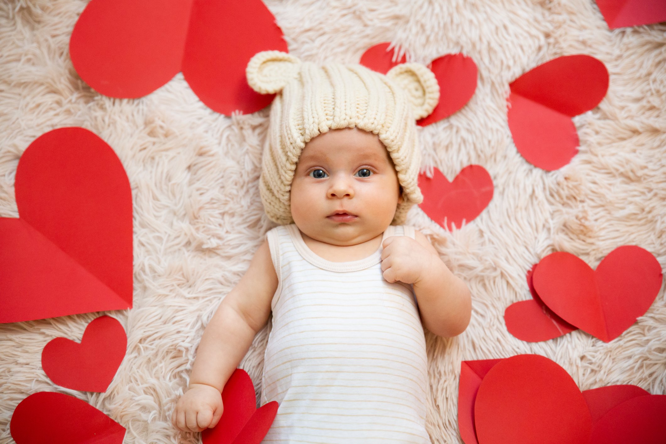 3 month old baby with teddy bear hat and t-shirt photographed with red hearts