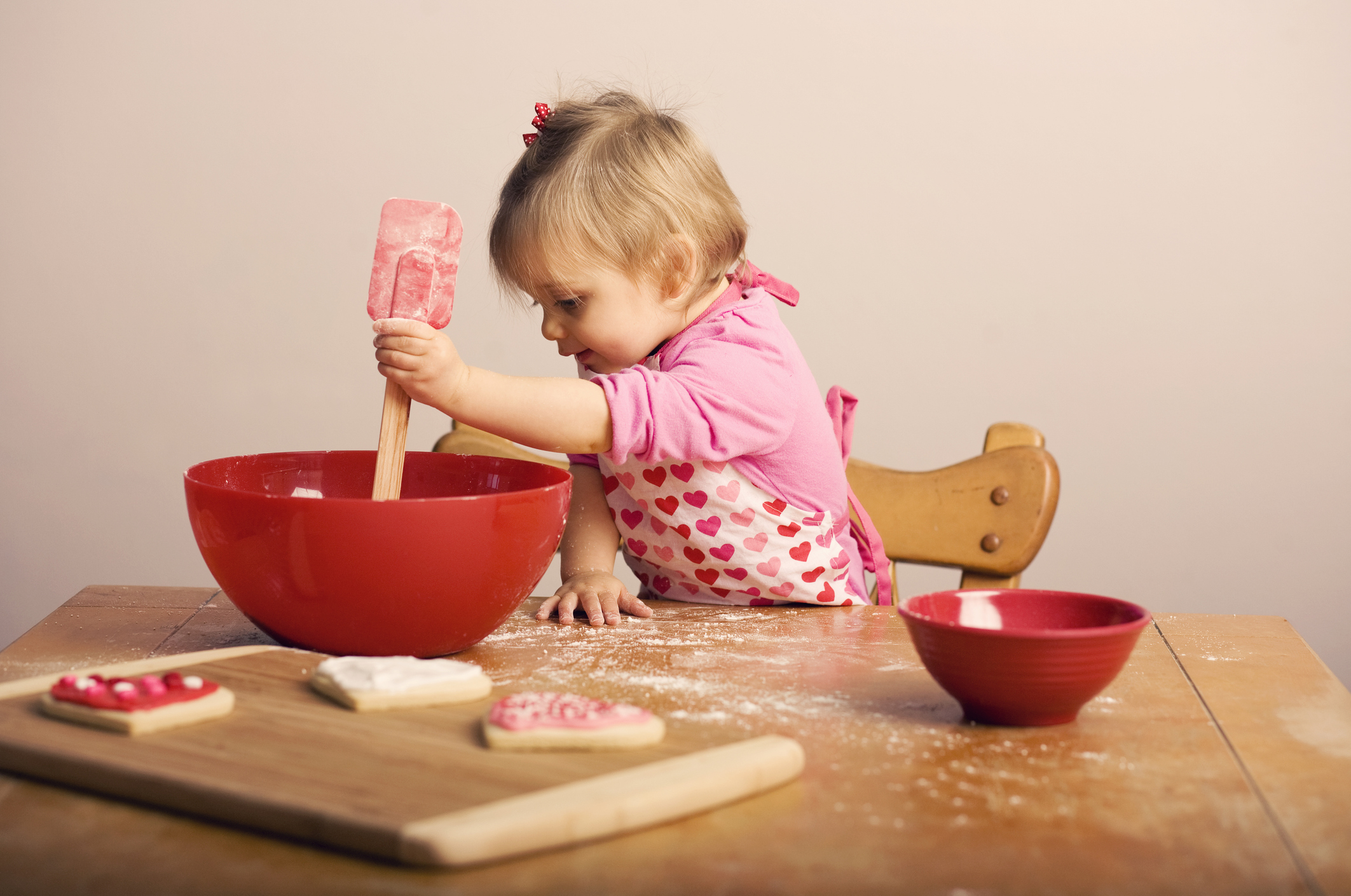 Toddler age girl baking cookies in the kitchen.